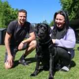 Mito und Christina Temelkov sitzen mit ihrem Hund Bobby in ihrem Garten in Dortmund-Berghofen und lächeln in die Kamera.