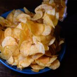 Eine Schüssel mit Kartoffelchips steht auf einem Tisch.