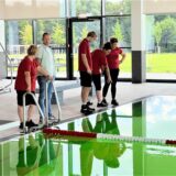 Mitarbeiter der GSW stehen an einem Beckenrand im neuen Häupenbad und beoachten, wie sich das Wasser verfärbt.