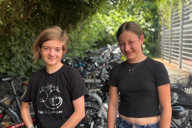 Zwei Schüler des RTG in Schwerte stehen vor Fahrradständern und schauen lächelnd in die Kamera.