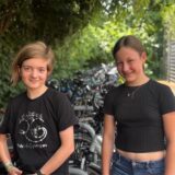 Zwei Schüler des RTG in Schwerte stehen vor Fahrradständern und schauen lächelnd in die Kamera.