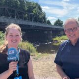 Wickedes Bürgermeister Martin Michalzik und Reporterin Lina Wiggeshoff stehen vor der alten Ruhrbrücke in Wickede.