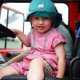 Ein junges Kind sitzt am Lenkrad eines Feuerwehrwagens.
