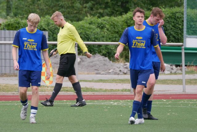 Spieler und Linienrichter stehen auf dem Platz.