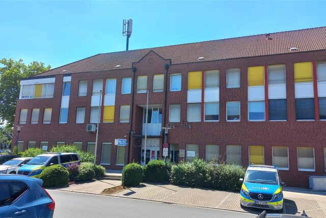 Blick auf das rote Backsteingebäude der Polizeiwache in Kamen. Rechts ist ein Streifenwagen auf einem Parkplatz zu sehen.