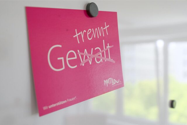 Auf einem roten Schild steht in weißer Schrift das Wort Gewalt. Die Silbe -walt ist durchgestrichen. Darüber steht das Wort trennt, sodass das neue Wort gelesen, getrennt ergibt.