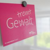 Auf einem roten Schild steht in weißer Schrift das Wort Gewalt. Die Silbe -walt ist durchgestrichen. Darüber steht das Wort trennt, sodass das neue Wort gelesen, getrennt ergibt.