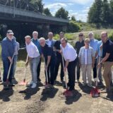 Viele Beteiligte des Brückenneubaus in Wickede stehen mit Spaten an der Baustelle