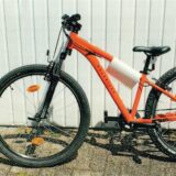 Ein orangefarbenes Mountainbike der Marke Rockrider steht vor einem weißen Hintergrund.