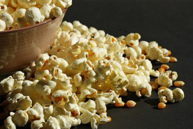 Popcorn sowie Popcornmais liegen in einer Schüssel und daneben.