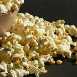 Popcorn sowie Popcornmais liegen in einer Schüssel und daneben.