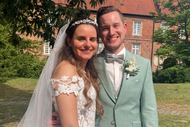 Sebastian und Jacqueline Schweinforth stehen vor ihrer kirchlichen Trauung auf einer Wiese vor dem Schloss Herten.
