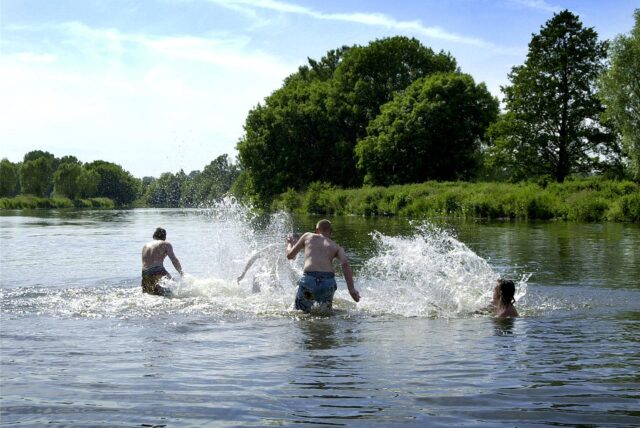 Drei Menschen laufen an einem Sommertag in die Ruhr.