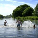 Drei Menschen laufen an einem Sommertag in die Ruhr.