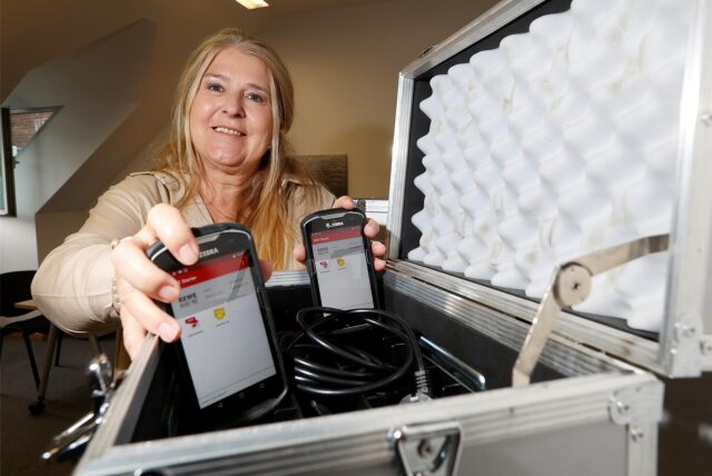 Inventur-Service-Geschäftsführerin Natascha Wiegard mit Inventurgeräten, die einem Smartphone ähnlich sehen. Sie sind normalerweise in einem Koffer verstaut, hier zeigt sie die Geräte in die Kamera.