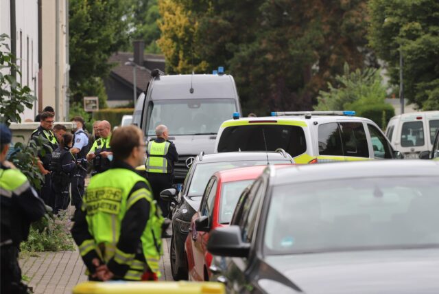 Zahlreiche Einsatzkräfte von Polizei, Rettungsdienst und Feuerwehr stehen zwischen Fahrzeugen vor einem Wohngebäude in Unna-Königsborn am Dienstag, 8. Juli.