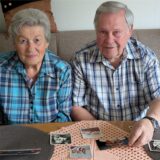 Eine Frau und ein Mann sitzen auf einem Sofa und schauen sich Fotos an.