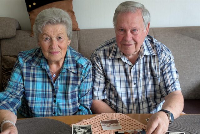 Eine Frau und ein Mann sitzen auf einem Sofa und schauen sich Fotos an.