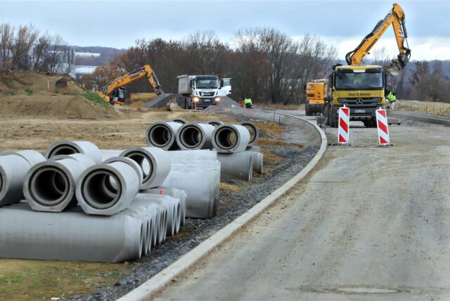 An einer Straßenbaustelle in Unna liegen Rohre aus Beton. Im Hintergrund stehen Baufahrzeuge