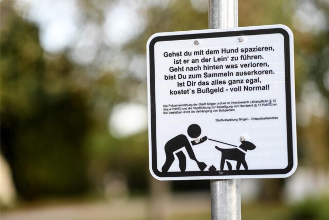 Singen Am Hohentwiel: Ein Schild mit der Aufschrift „Gehst Du mit dem Hund spazieren, ist er an der Lein‘ zu führen. Geht nach hinten was verloren, bist Du zum Sammeln auserkoren. Ist Dir das alles ganz egal, kostet’s Bußgeld – voll normal!“ hängt an einem Pfosten am Eingang zum alten Friedhof.