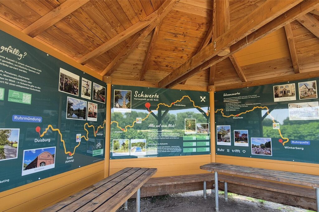 Blick in die hölzerne Rasthütte am Ruhrtalradweg in Schwerte. An den Wänden hängen Infotafeln, die über Schwerte informieren. Blick in die hölzerne Rasthütte am Ruhrtalradweg in Schwerte. An den Wänden hängen Infotafeln, die über Schwerte informieren.