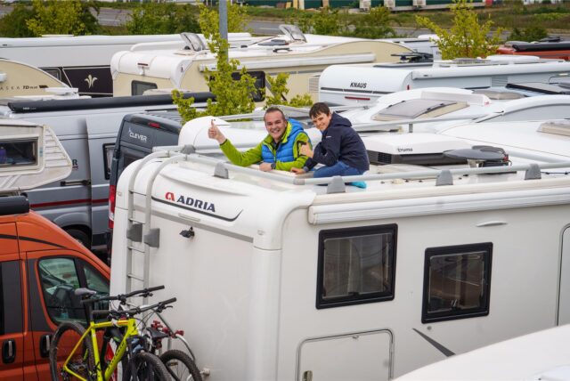 Ein Camper schaut mit seinem Sohn oben aus seinem Wohnmobil heraus