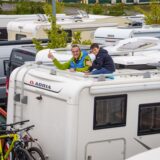 Ein Camper schaut mit seinem Sohn oben aus seinem Wohnmobil heraus