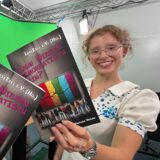 Jule Scherbes (15) und Hannah Balmaceda (16) halten vor einem Greenscreen das Demokratie-Buch in die Kamera.