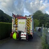 Ein Feuerwehrfahrzeug steht an einem Zaun.