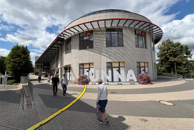 Ein Netz umspannt die Fassade des Einkaufszentrum Neue Mühle in Unna. Fußgänger laufen daran vorbei.