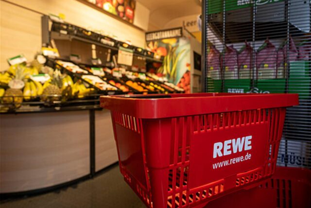 Das Logo der Supermarktkette Rewe ist auf einem Einkaufskorb zu sehen.