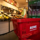 Das Logo der Supermarktkette Rewe ist auf einem Einkaufskorb zu sehen.