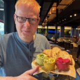 Reporter Markus Geling sitzt bei WIlma Wunder in Recklinghausen und hält einen Teller mit Brot und Dips.