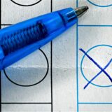 Nahaufnahme eines Wahlzettels mit blauem Stift, bei dem ein Kästchen mit einem Kreuz markiert ist.