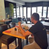 Ein Mann sitzt an einem Tisch in einem Sushi Restaurant in Unna. Er isst mit zwei Holzstäbchen Sushi von einer Holzplatte.