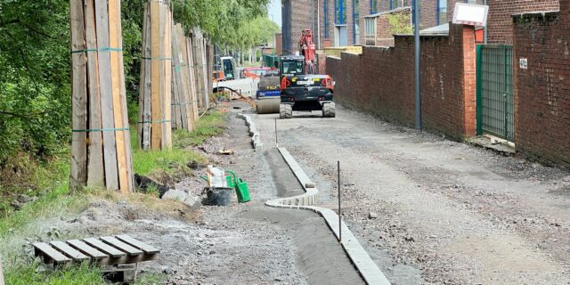 Die Saarbrücker Straße wird in einen Radweg umgebaut. Auf der Trasse rollt ein Bagger, links im Bild ist zu erkennen, wie die Stämme der Alleenbäume zum Schutz mit Holzlatten eingepackt sind.