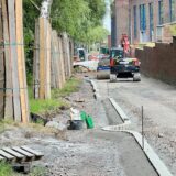 Die Saarbrücker Straße wird in einen Radweg umgebaut. Auf der Trasse rollt ein Bagger, links im Bild ist zu erkennen, wie die Stämme der Alleenbäume zum Schutz mit Holzlatten eingepackt sind.