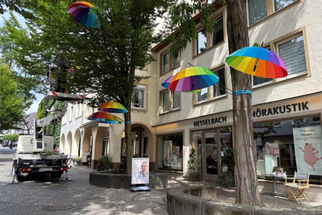 Bunte Regenschirme werden in den Bäumen an der Wasserstraße in Unna angebracht