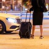 Eine Frau wartet abends nahe einem Hauptbahnhof auf ein Taxi.
