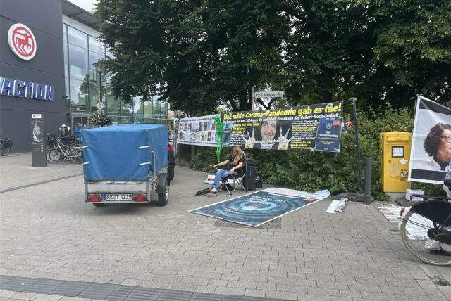Eine Frau sitzt vor den Plakaten.