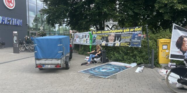 Eine Frau sitzt vor den Plakaten.