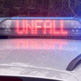 Blaulicht auf einem Polizeiauto mit dem Schriftzug ‚UNFALL‘ in roter LED-Anzeige