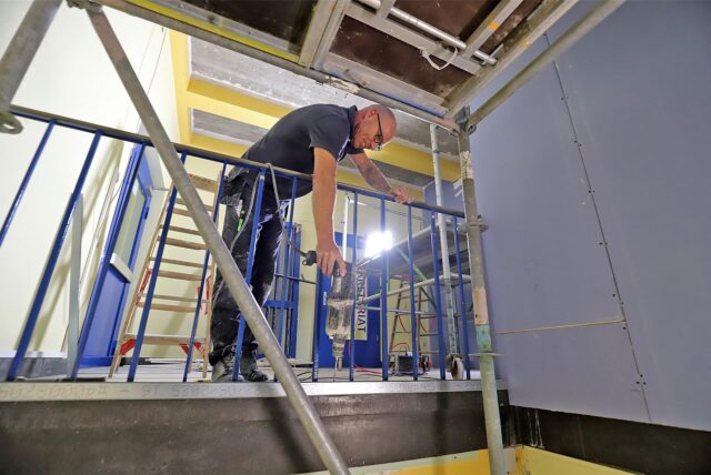 Bauarbeiten in der Preinschule in Oberaden. Ein Arbeiter hängt sich halb über ein blaues Geländer.