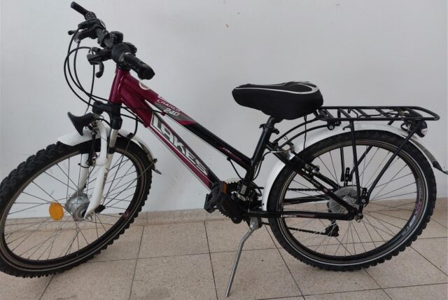 Die Polizei hat ein schwarz-rotes Kinderfahrrad der Marke „Lakes“ vor einer weißen Wand fotografiert.
