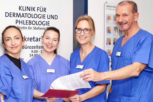 Zenaida Numanovic und Dr. Rosanna Auer (Oberärztinnen), Dr. Stefanie Boms (Chefärztin) und Prof. Dr. Thilo Gambichler (Leitender Oberarzt und Ärztlicher Leiter Hautzentrum Unna) stehen vor dem Sekretariat der Klinik für Dermatologie und Phlebologie im Christlichen Klinikum Unna.