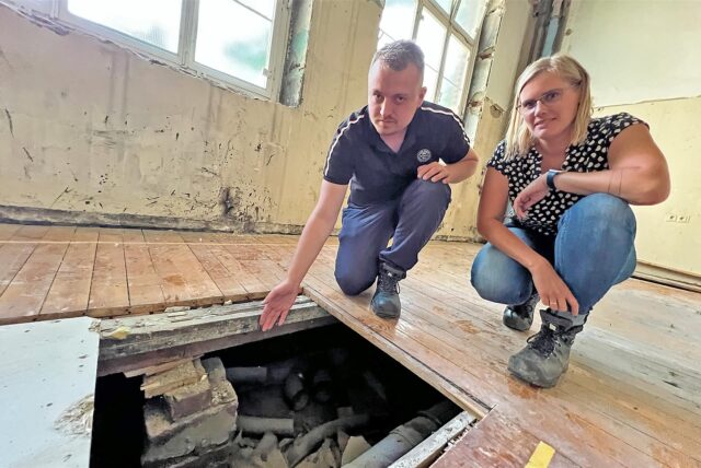 Marion Wenner und Stefan Griewel vom Gebäudemanagement der Stadt Kamen vor einem Loch im Holzboden der Josefschule.