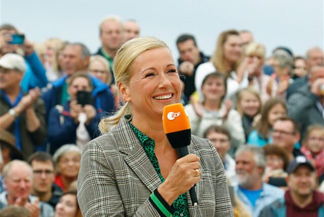 Andrea Kiewel, Moderatorin des „ZDF-Fernsehgartens“ bei einer Sendung. Sie hält ein Mikrofon des ZDF in der Hand.