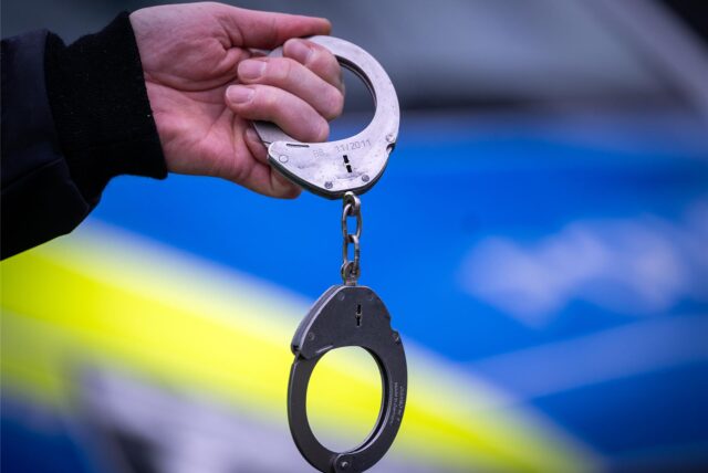Handschellen vor Polizeiwagen