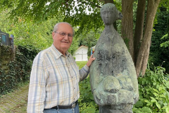 Wolfgang Miehle steht neben einer Bronzefigur in seinem Garten.