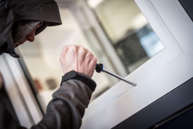Ein Einbrecher hebelt ein Fenster auf. (Symbolbild)